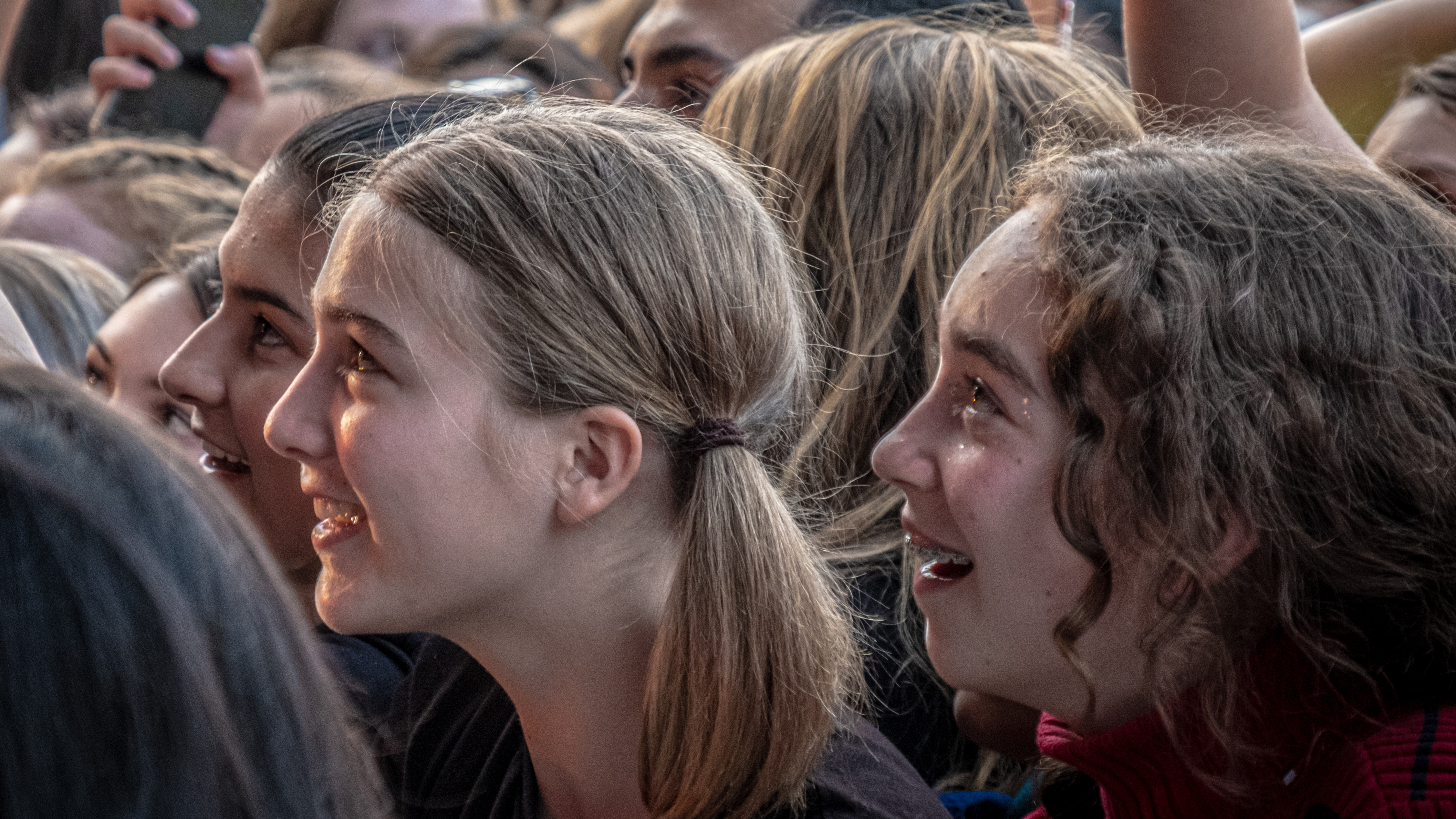 Smiling, emotional teen girls in a concert audience