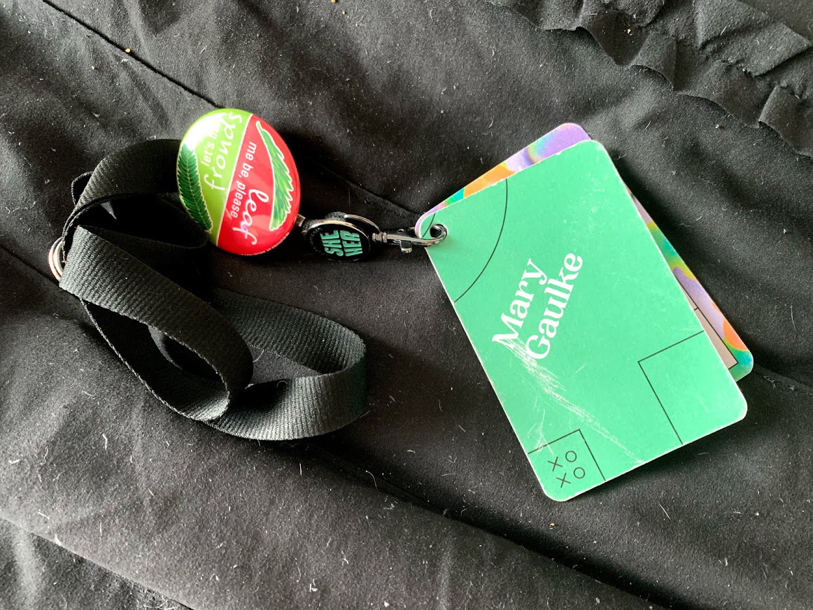 Mary's nametag, pronoun pin, and frond pin from XOXO 2019